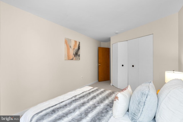 bedroom featuring baseboards, light carpet, and a closet