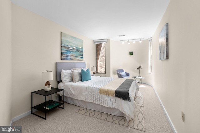 bedroom featuring baseboards, track lighting, visible vents, and carpet