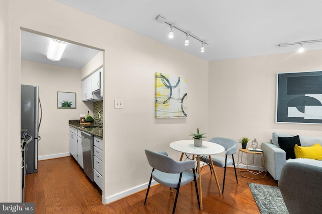 dining area featuring track lighting, wood finished floors, and baseboards