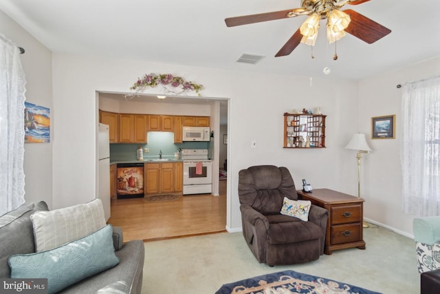 living area with visible vents, baseboards, a ceiling fan, and light carpet