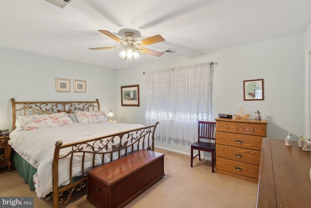 bedroom with visible vents, a ceiling fan, and light carpet