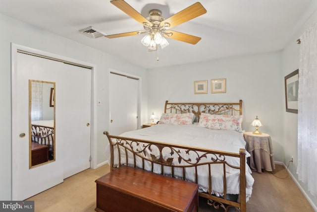 bedroom featuring baseboards, light carpet, two closets, a ceiling fan, and visible vents