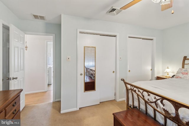 bedroom with light carpet, visible vents, baseboards, and two closets