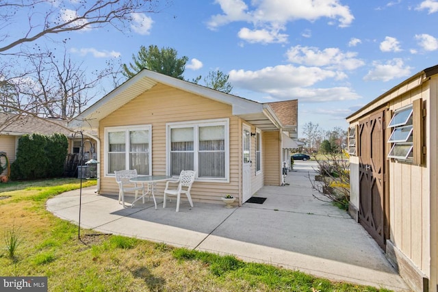 rear view of property featuring a yard, a patio, and roof with shingles