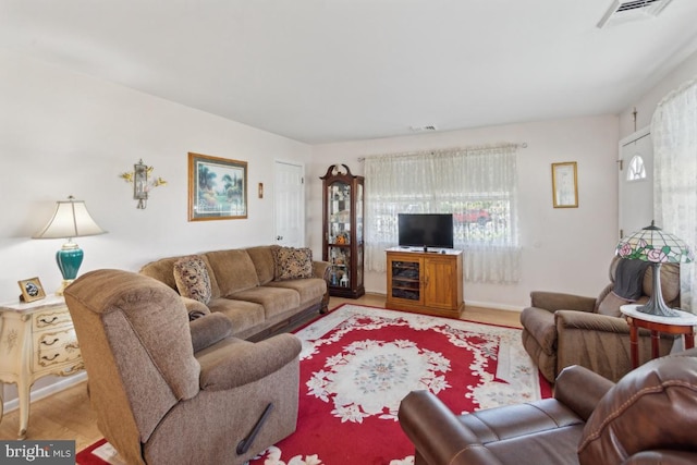 living room with wood finished floors, baseboards, and visible vents