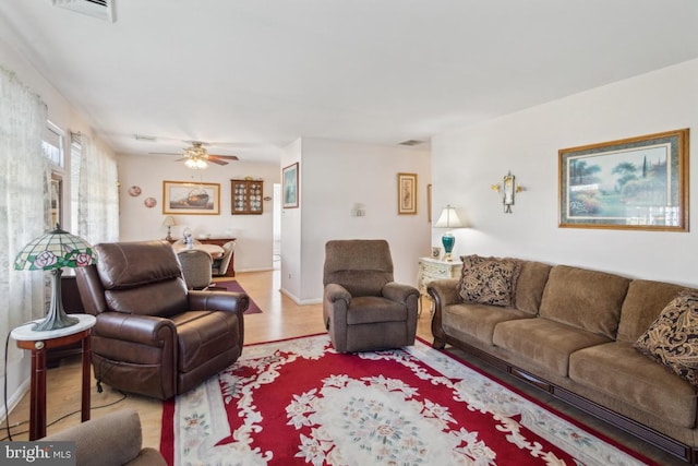 living room featuring light wood-type flooring, ceiling fan, baseboards, and visible vents