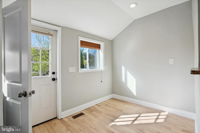 doorway to outside with visible vents, light wood-style flooring, vaulted ceiling, and baseboards