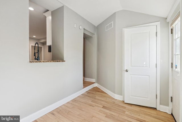 hall featuring wood finished floors, baseboards, vaulted ceiling, and visible vents