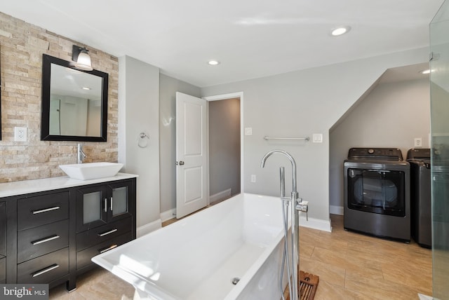 full bath with independent washer and dryer, vanity, baseboards, and recessed lighting