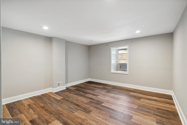 empty room featuring dark wood-style flooring, baseboards, visible vents, and recessed lighting