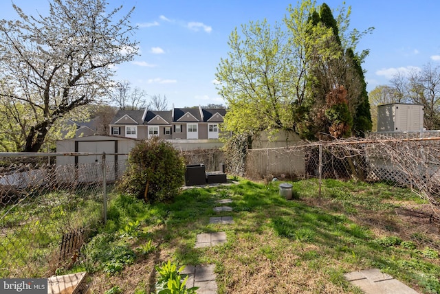 view of yard with a fenced backyard, an outdoor structure, and a storage unit