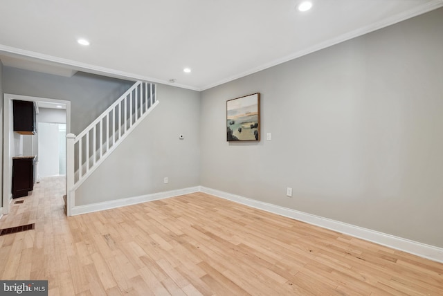 spare room with stairs, light wood finished floors, baseboards, and ornamental molding