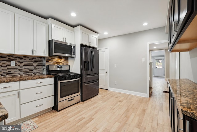 kitchen featuring stainless steel appliances, tasteful backsplash, light wood-style floors, and dark stone counters