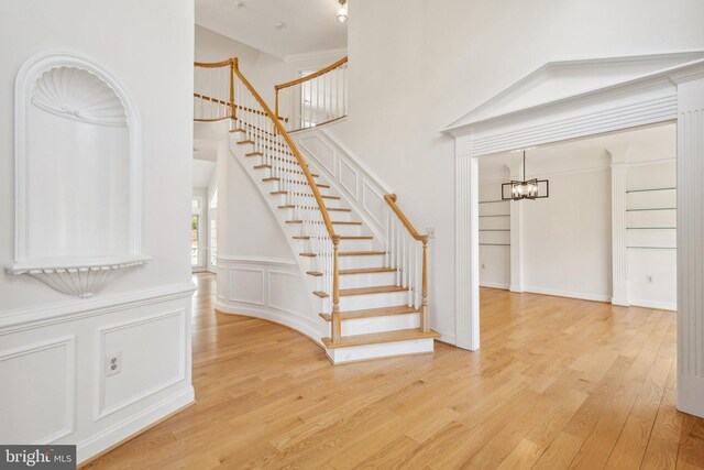 9313 Braymore Cir, Fairfax Station, VA 22039 - staircase featuring a towering ceiling, wood finished floors, a chandelier, and a decorative wall