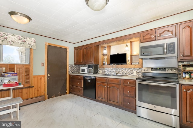 kitchen with a sink, light countertops, a wainscoted wall, and stainless steel appliances