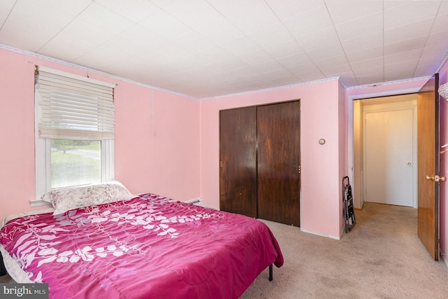 bedroom featuring a closet, ornamental molding, and light carpet