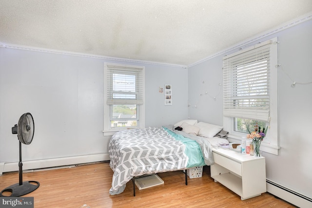 bedroom featuring a textured ceiling, a baseboard radiator, ornamental molding, and light wood-style flooring