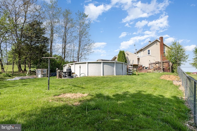 view of yard with fence, a deck, and a pool