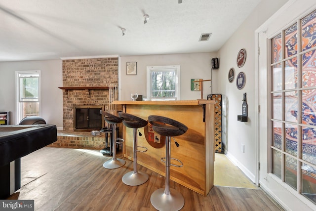 7303 Westwind Ct, Bowie, MD 20715 - bar with wood finished floors, a brick fireplace, baseboards, visible vents, and a bar