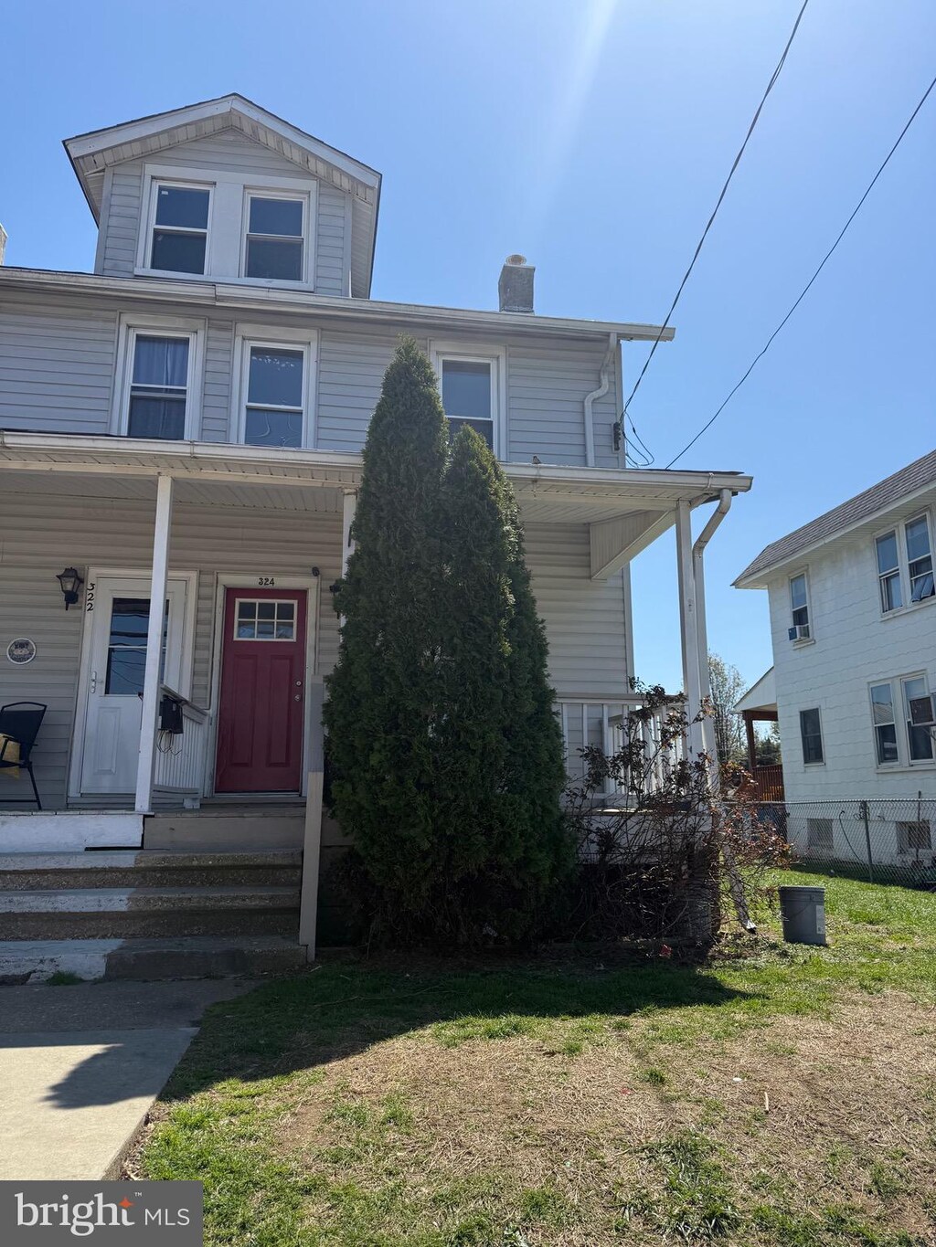 view of front of house featuring covered porch, a chimney, and a front yard