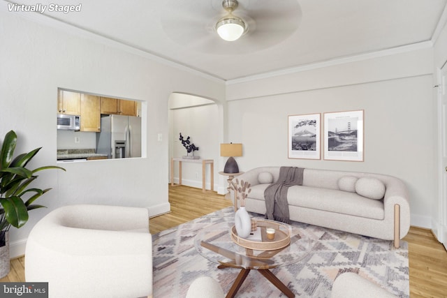 living area with light wood-style flooring, crown molding, and ceiling fan