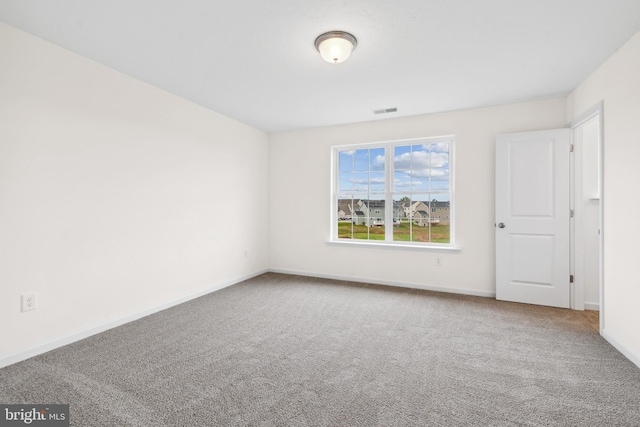 carpeted spare room featuring visible vents and baseboards
