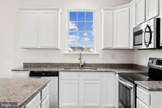 kitchen featuring stone counters, a sink, white cabinetry, and stainless steel appliances