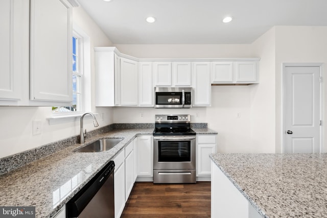 kitchen featuring light stone counters, a sink, dark wood finished floors, and stainless steel appliances