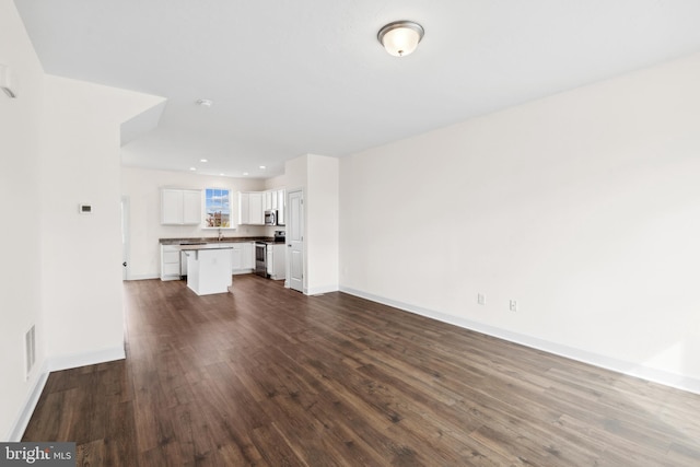unfurnished living room with baseboards, dark wood-style floors, visible vents, and recessed lighting
