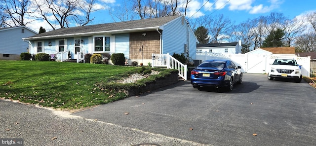 ranch-style home with aphalt driveway, a front yard, fence, and a gate