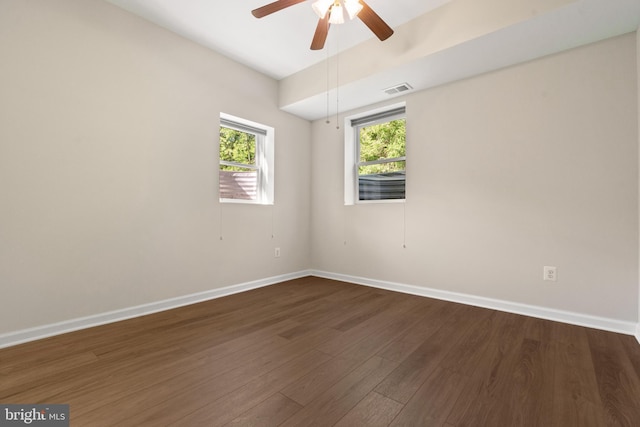 empty room featuring dark wood-style flooring, baseboards, visible vents, and ceiling fan