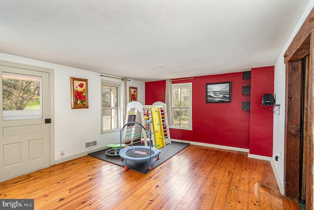 exercise area with visible vents, baseboards, and wood-type flooring