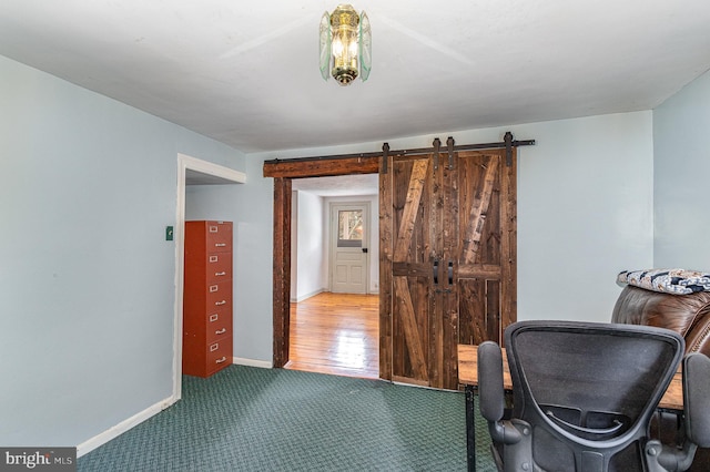 office area with a barn door, carpet, and baseboards