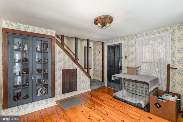 foyer entrance with wallpapered walls, baseboards, stairs, and wood-type flooring