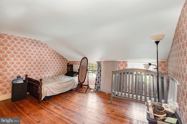 bedroom featuring wallpapered walls, vaulted ceiling, and wood-type flooring