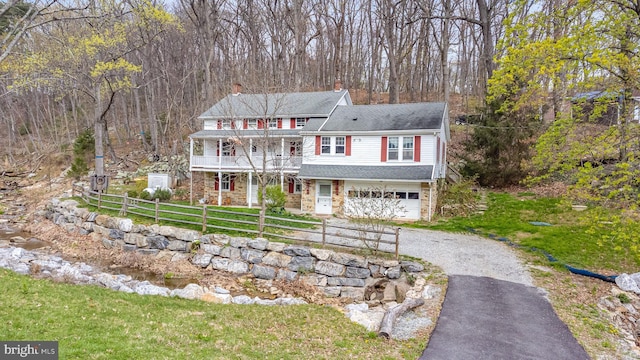 traditional-style house with a garage, a chimney, aphalt driveway, fence, and a front yard