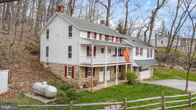 view of front of property with a chimney, fence, a front lawn, a balcony, and driveway