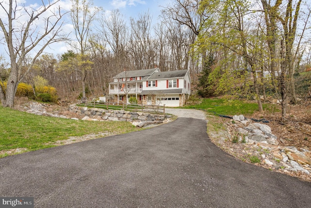 view of front of house featuring an attached garage, aphalt driveway, and a front yard
