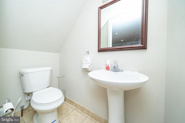 half bath featuring toilet, baseboards, lofted ceiling, and tile patterned flooring