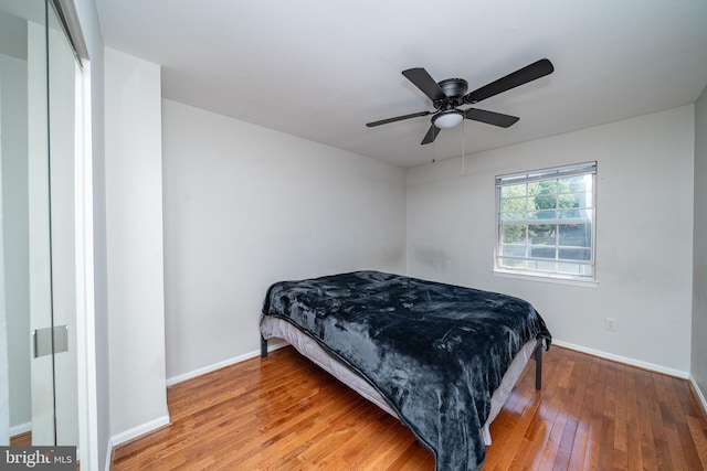 bedroom with wood-type flooring, a ceiling fan, and baseboards