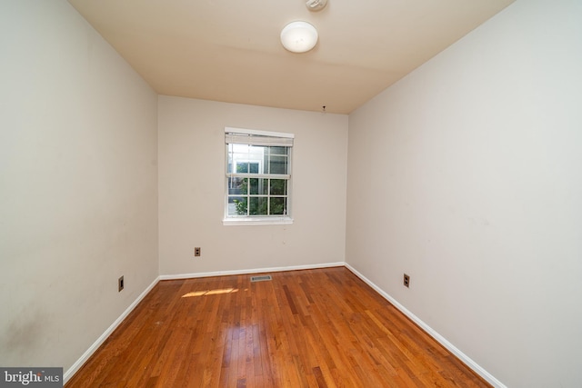 spare room featuring baseboards, visible vents, and wood finished floors