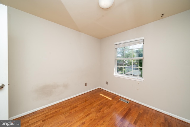 spare room featuring baseboards, hardwood / wood-style flooring, and visible vents