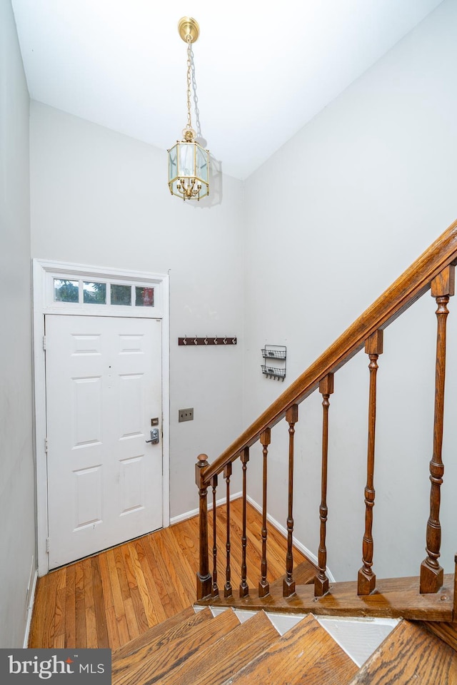 foyer entrance with an inviting chandelier, baseboards, stairway, and light wood-style flooring