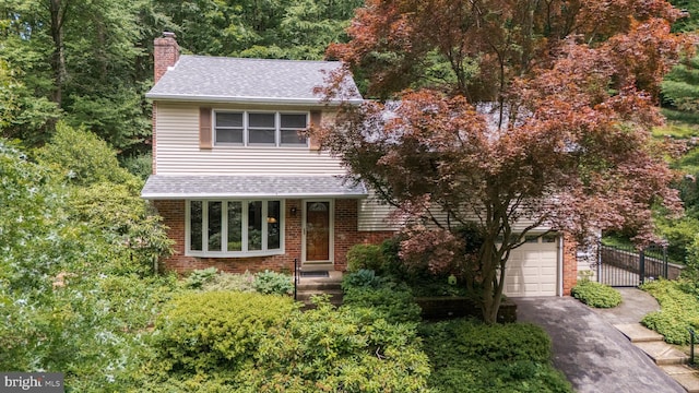 552 Brookwood Rd, Wayne, PA 19087 - view of front facade with a chimney, a garage, driveway, a shingled roof, and brick siding