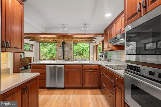 552 Brookwood Rd, Wayne, PA 19087 - kitchen with appliances with stainless steel finishes, under cabinet range hood, decorative backsplash, light countertops, and light wood-style floors