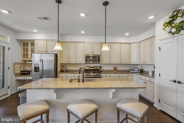 kitchen with light stone counters, a sink, stainless steel appliances, dark wood-type flooring, and visible vents