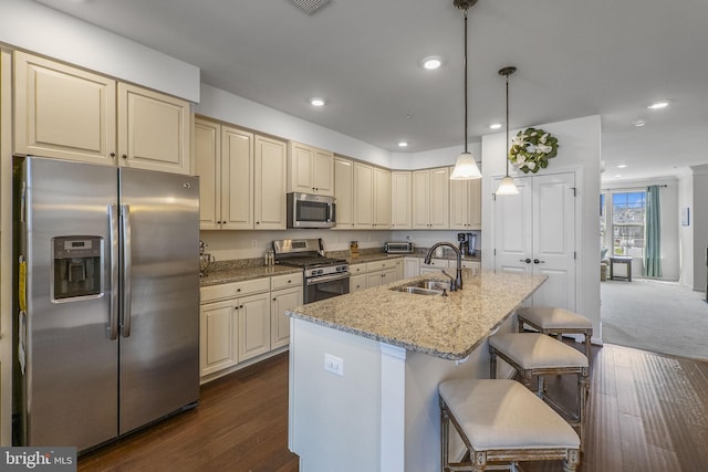 kitchen with a sink, an island with sink, stainless steel appliances, and cream cabinetry