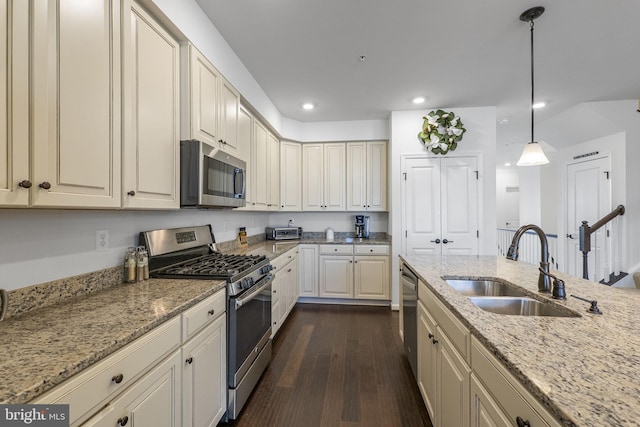 kitchen featuring appliances with stainless steel finishes, a sink, recessed lighting, cream cabinetry, and dark wood-type flooring