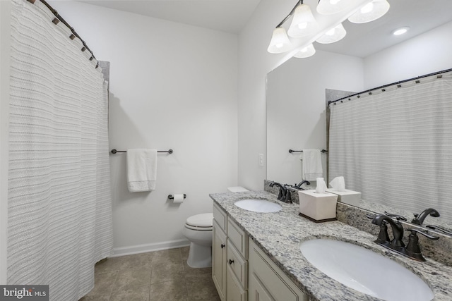 bathroom with a sink, baseboards, toilet, and double vanity