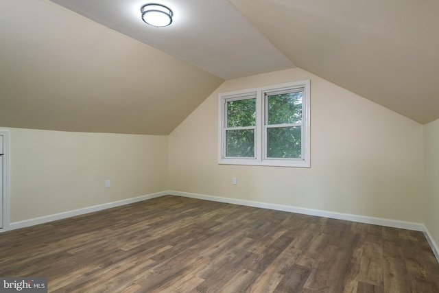 bonus room featuring dark wood-type flooring, baseboards, and vaulted ceiling
